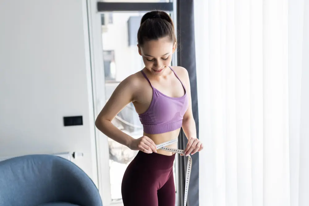 Sporty young woman and measure around her body at home