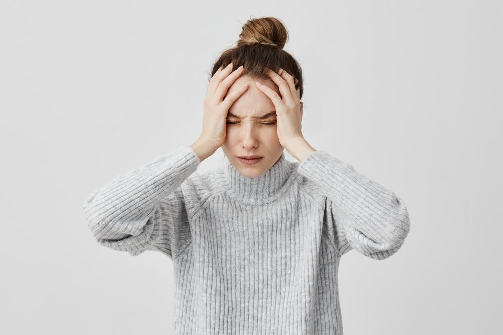 Exhausted young woman touching her head with eyes closed