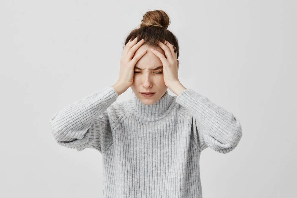 Female holding her head in pain with both hands from migraine