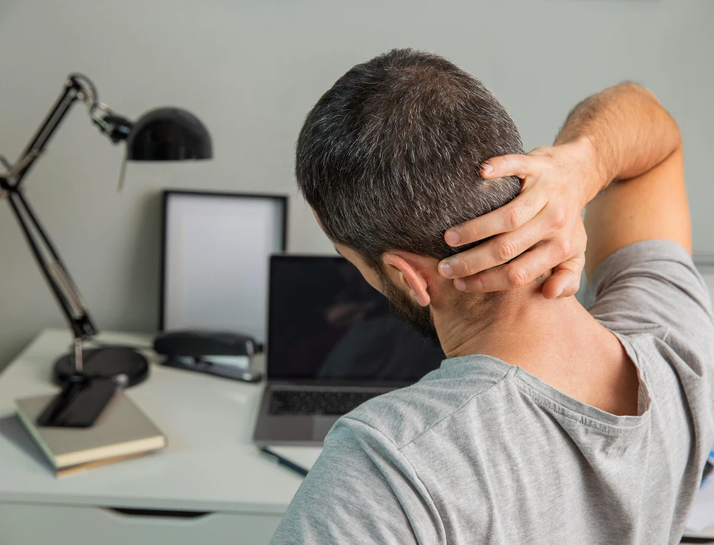 Person holding neck due to stiffness and pain