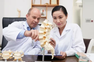Doctor showing spine model to explain disc degeneration and spinal changes