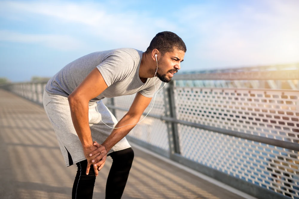 Runner experiencing outer knee pain caused by IT band tightness and strain