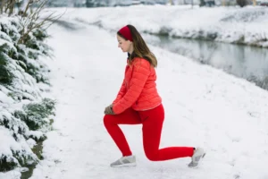 Person holding a painful knee while outdoors in cold weather