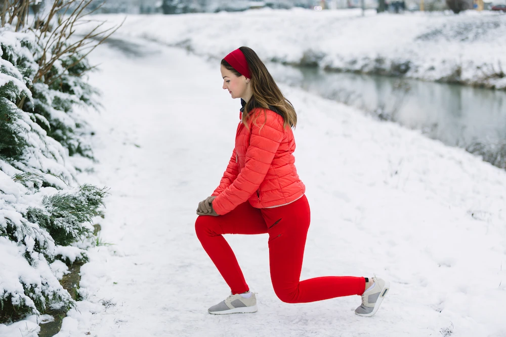Person holding a painful knee while outdoors in cold weather