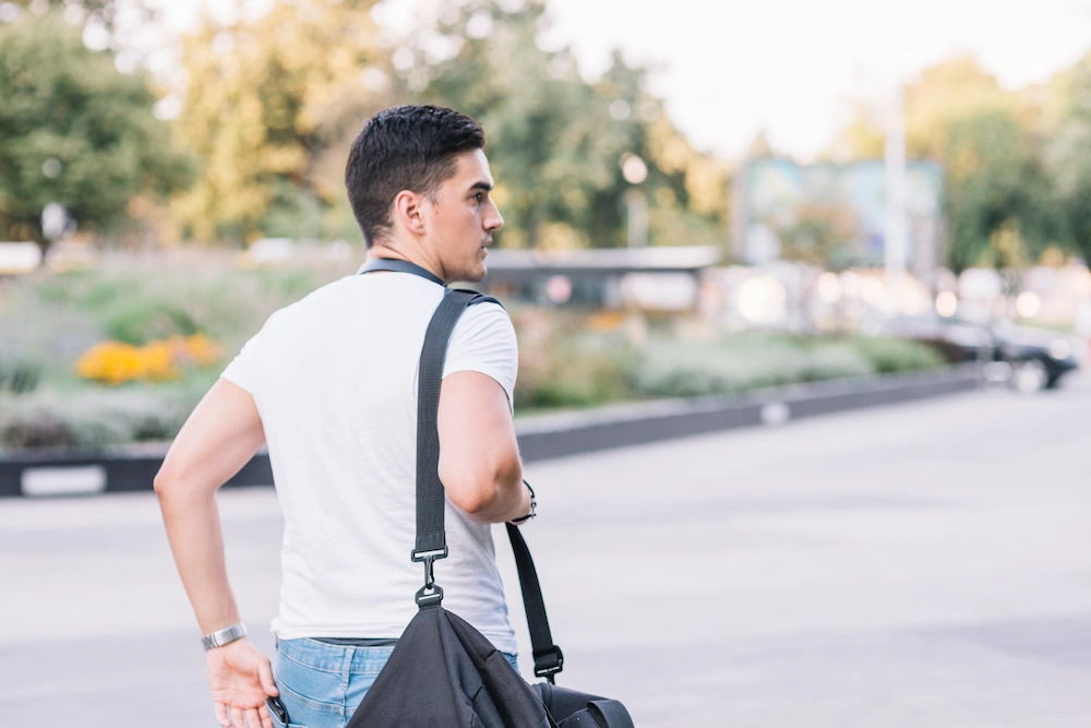 Person carrying a heavy shoulder bag while experiencing neck discomfort